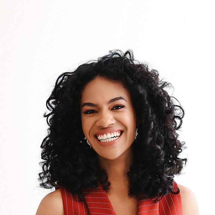 Dayane Martins sorrindo, de colete vermelho risca de giz